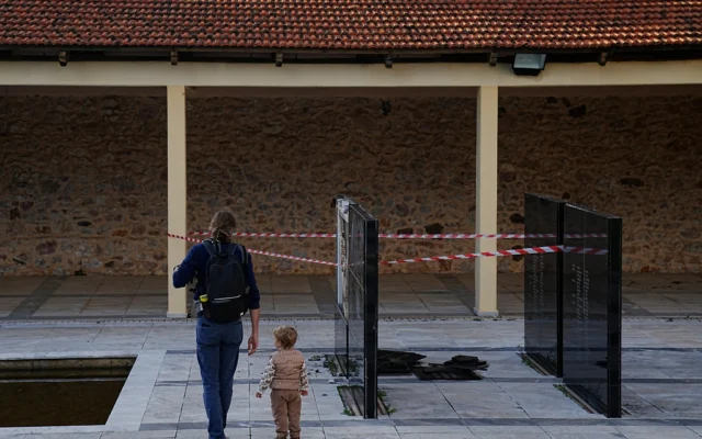 Des passants devant une plaque commémorative vandalisée au stand de tir de Kaisariani, dans la banlieue d'Athènes, en Grèce, le 16 février 2026. (Crédit: AP/ Petros Giannakouris) Des passants devant une plaque commémorative vandalisée au stand de tir de Kaisariani, dans la banlieue d'Athènes, en Grèce, le 16 février 2026. (Crédit: AP/ Petros Giannakouris)