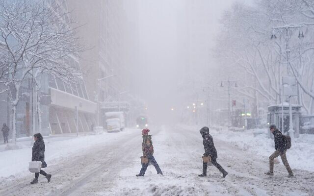 Des piétons traversent la 42e rue près de Bryant Park pendant une tempête de neige, le 23 février 2026, à New York. (Crédit : AP/Seth Wenig) Des piétons traversent la 42e rue près de Bryant Park pendant une tempête de neige, le 23 février 2026, à New York. (Crédit : AP/Seth Wenig)