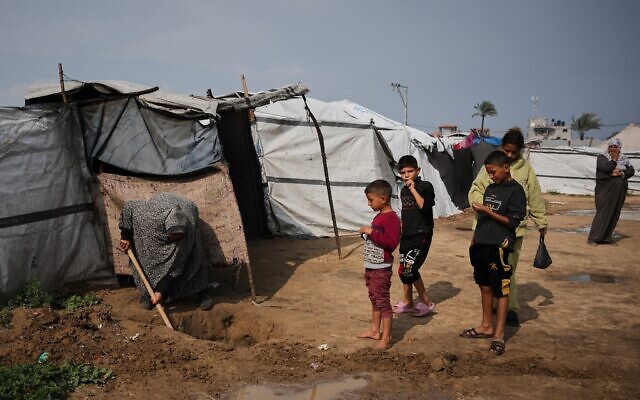 Lubna Abu Sirya creusant un petit canal pour évacuer l'eau de pluie qui a inondé sa tente à Deir al-Balah, dans le centre de la bande de Gaza, le 24 février 2026. (Crédit : Abdel Kareem Hana/AP) Lubna Abu Sirya creusant un petit canal pour évacuer l'eau de pluie qui a inondé sa tente à Deir al-Balah, dans le centre de la bande de Gaza, le 24 février 2026. (Crédit : Abdel Kareem Hana/AP)