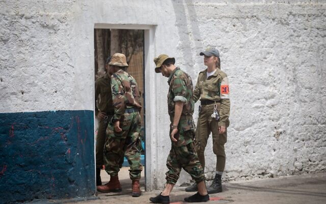 Illustration : Un officier de la police militaire (à droite) conduisant deux soldats israéliens emprisonnés à travers une porte de la prison n° 4, la plus grande prison militaire d'Israël, située dans la base militaire de Tzrifin, dans le centre du pays, le 26 avril 2018. (Crédit : Miriam Alster/Flash90)