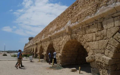 Des Israéliens et des touristes se promènent sur la plage sur laquelle s'est effondré une arche de l'aqueduc de Césarée, vieille de 2 000 ans, le 21 août 2023. (Michael Giladi/Flash90)