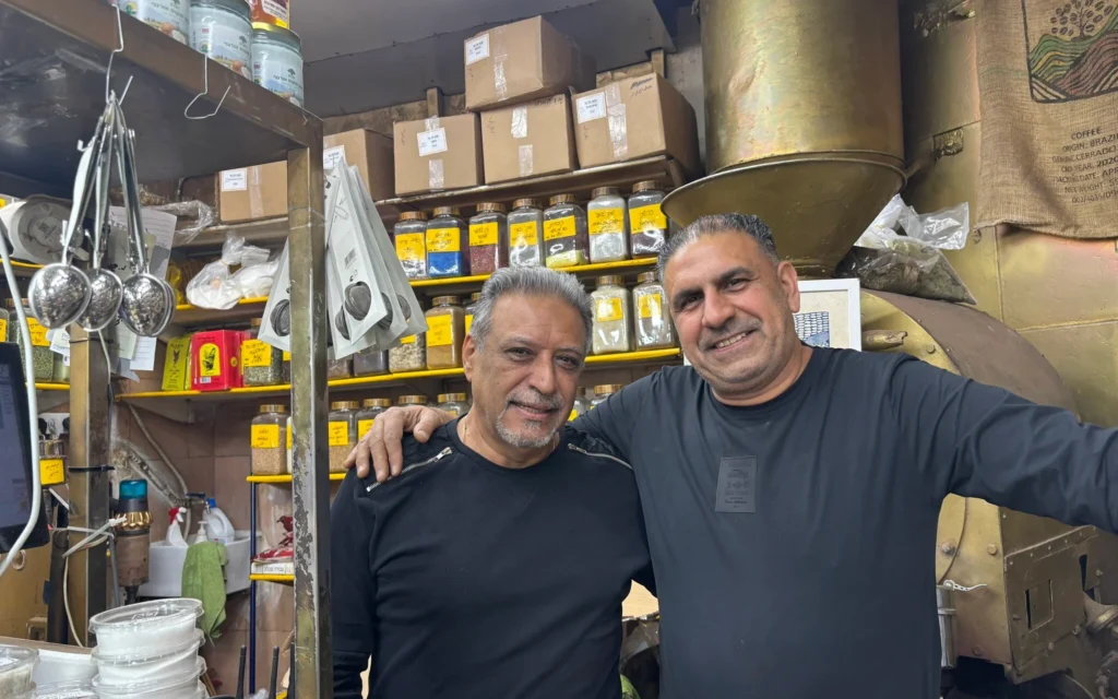 Bijan Barchorderi, propriétaire d’un restaurant (à gauche), et Isaac Simanian, commerçant, tous deux Juifs originaires d’Iran, vendent des spécialités persanes au marché Levinsky, dans le sud de Tel Aviv, le 22 janvier 2026. (Crédit : Sharon Wrobel/The Times of Israel)