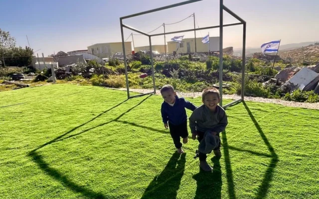 Deux garçons jouant sur un terrain de football nouvellement aménagé dans le hameau palestinien d'Umm al-Khair en Cisjordanie, avec en arrière-plan des maisons israéliennes récemment construites, le 2 février 2026. (Crédit : Jeremy Sharon/Times of Israel) Deux garçons jouant sur un terrain de football nouvellement aménagé dans le hameau palestinien d'Umm al-Khair en Cisjordanie, avec en arrière-plan des maisons israéliennes récemment construites, le 2 février 2026. (Crédit : Jeremy Sharon/Times of Israel)