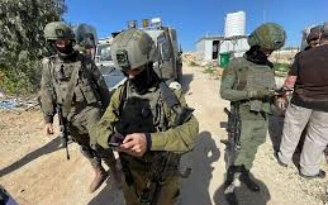 Des soldats de l'armée israélienne lisent un ordre de fermeture de zone militaire aux militants pour la coexistence venus planter des arbres dans le village palestinien d'Umm al-Khair, en Cisjordanie, le 2 février 2026. (Crédit : Jeremy Sharon / The Times of Israel)