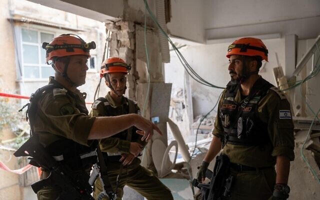 Le chef du Commandement du Front intérieur, le général de division Shaï Klapper (à gauche), aux côtés d'autres officiers dans une maison du centre d'Israël touchée par une bombe à fragmentation iranienne, le 9 mars 2026. (Crédit : Armée israélienne)