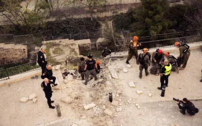 Des membres des forces de sécurité israéliennes se trouvent sur les lieux où un fragment de missile balistique iranien intercepté s'est écrasé dans le quartier juif de la Vieille Ville de Jérusalem le 20 mars 2026, endommageant une route et un mur. (Crédit : Porte-parole de Tsahal)
