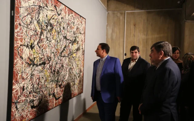 Le ministre iranien de la Culture, Ali Jannati (à droite), examine la « Mural on Indian Red Ground » (1950) de l'artiste américain Jackson Pollock le jour du vernissage d'une exposition d'art moderne au Musée d'art contemporain de Téhéran, le 20 novembre 2015. (ATTA KENARE / AFP)