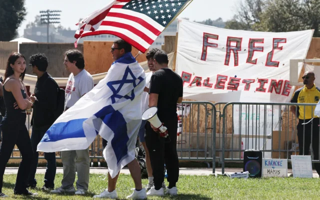 Un contre-manifestant porte un drapeau israélien tout en brandissant un drapeau américain près d’un campement pro-palestinien et anti-israélien sur le campus de l’Université de Californie à Los Angeles (UCLA), le 30 avril 2024 à Los Angeles, en Californie. (Crédit : MARIO TAMA / GETTY IMAGES NORTH AMERICA / Getty Images via AFP) Un contre-manifestant porte un drapeau israélien tout en brandissant un drapeau américain près d’un campement pro-palestinien et anti-israélien sur le campus de l’Université de Californie à Los Angeles (UCLA), le 30 avril 2024 à Los Angeles, en Californie. (Crédit : MARIO TAMA / GETTY IMAGES NORTH AMERICA / Getty Images via AFP)