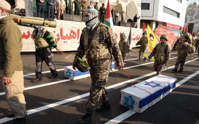 Des membres des forces paramilitaires iraniennes (Basij) tirent des caisses symbolisant des cercueils israéliens, lors d'un rassemblement anti-israélien visant à manifester leur solidarité avec les peuples palestinien et libanais, à Téhéran, le 10 janvier 2025. (Crédit : AFP)