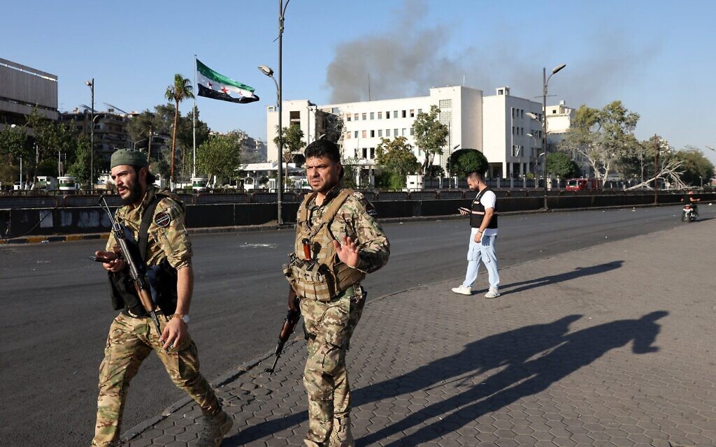Les forces de sécurité syriennes montant la garde devant le complexe de l'armée syrienne et du ministère de la Défense, fortement endommagé, à Damas, après les frappes israéliennes du 16 juillet 2025. (Crédit : Bakr ALkasem / AFP)