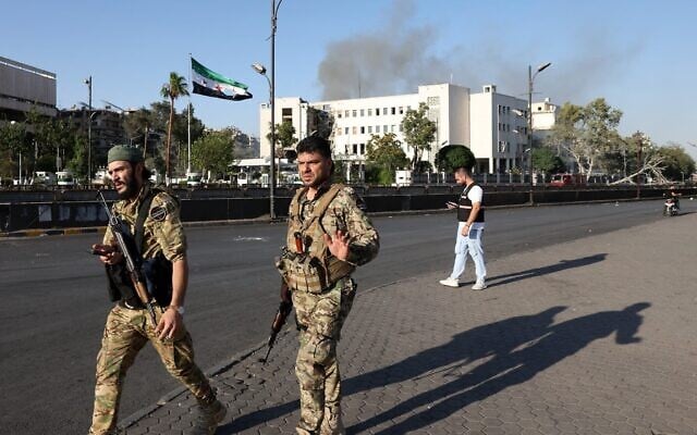 Les forces de sécurité syriennes montant la garde devant le complexe de l'armée syrienne et du ministère de la Défense, fortement endommagé, à Damas, après les frappes israéliennes du 16 juillet 2025. (Crédit : Bakr ALkasem / AFP)