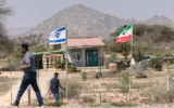 Des personnes passent devant les drapeaux d'Israël et du Somaliland, à l'entrée d'une ferme fruitière située entre la capitale, Hargeisa, et la ville portuaire de Berbera, en plein mois du Ramadan, au Somaliland, le 19 février 2026. (Tony KARUMBA / AFP)