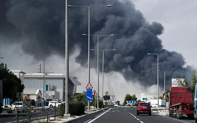 Des automobilistes passant devant un panache de fumée s'élevant d'une frappe iranienne signalée dans le quartier industriel de Doha, le 1ᵉʳ mars 2026. (Crédit : Mahmud Hams/AFP)