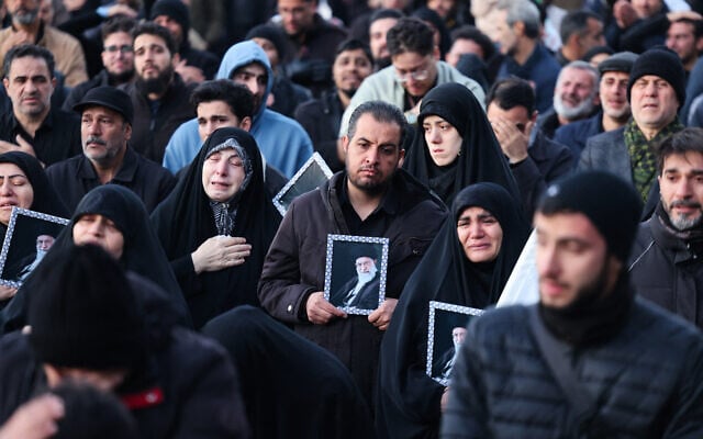 Des personnes tenant une affiche du guide suprême iranien, l'ayatollah Ali Khamenei, éliminé lors d'une frappe conjointe des États-Unis et d'Israël, alors qu'il se joint à d'autres personnes en deuil sur une place de Téhéran, le 1ᵉʳ mars 2026. L'ayatollah Ali Khamenei, guide suprême de l'Iran depuis 1989 et ennemi juré de l'Occident, a été tué lors de la première salve d'une attaque massive menée par les États-Unis et Israël qui s'est prolongée jusqu'au 1er mars, alors que les deux puissances cherchent à renverser la République islamique. (Crédit : Atta Kenare/AFP)
