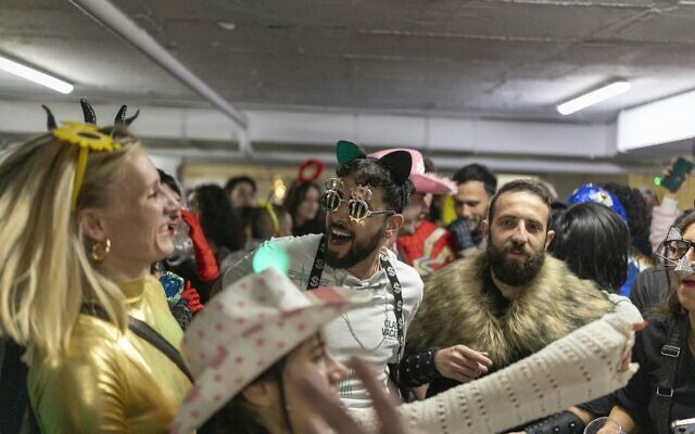 Des Israéliens déguisés rassemblés dans un parking du centre commercial Dizengoff de Tel Aviv utilisé comme abri pour célébrer la fête de Pourim, le 2 mars 2026. (Crédit : Ilia Yefimovich/AFP) Des Israéliens déguisés rassemblés dans un parking du centre commercial Dizengoff de Tel Aviv utilisé comme abri pour célébrer la fête de Pourim, le 2 mars 2026. (Crédit : Ilia Yefimovich/AFP)