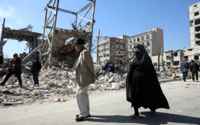 Un homme et une femme passent devant des bâtiments détruits par des frappes aériennes dans le centre de Téhéran, le 4 mars 2026. (Crédit: AFP)