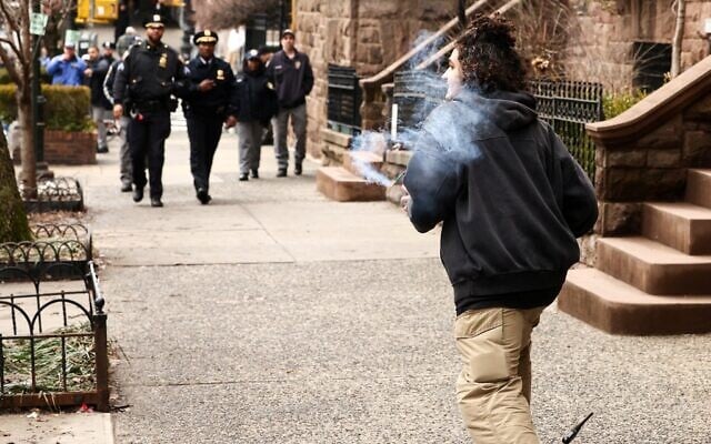 Un militant de gauche tient un engin explosif artisanal avant de le lancer en direction des forces de police lors d'une manifestation organisée par l'influenceur d'extrême droite Jake Lang contre la prétendue « islamisation » de New York, devant Gracie Mansion, le 7 mars 2026. (Crédit : CHARLY TRIBALLEAU / AFP) Un militant de gauche tient un engin explosif artisanal avant de le lancer en direction des forces de police lors d'une manifestation organisée par l'influenceur d'extrême droite Jake Lang contre la prétendue « islamisation » de New York, devant Gracie Mansion, le 7 mars 2026. (Crédit : CHARLY TRIBALLEAU / AFP)