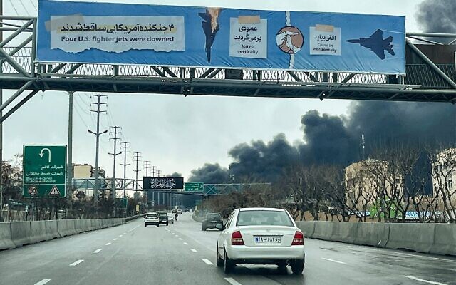 Des véhicules circulant sur une autoroute près de panaches de fumée noire s'élevant, à Téhéran, le 8 mars 2026. (Crédit : AFP) Des véhicules circulant sur une autoroute près de panaches de fumée noire s'élevant, à Téhéran, le 8 mars 2026. (Crédit : AFP)