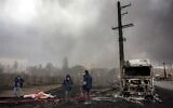 Un membre de la défense civile iranienne se tenant avec un tuyau d'arrosage à côté d'un camion-citerne détruit près d'un incendie qui fait toujours rage après une frappe aérienne nocturne sur la raffinerie de pétrole de Shahran, au nord-ouest de Téhéran, le 8 mars 2026. (Crédit : AFP)