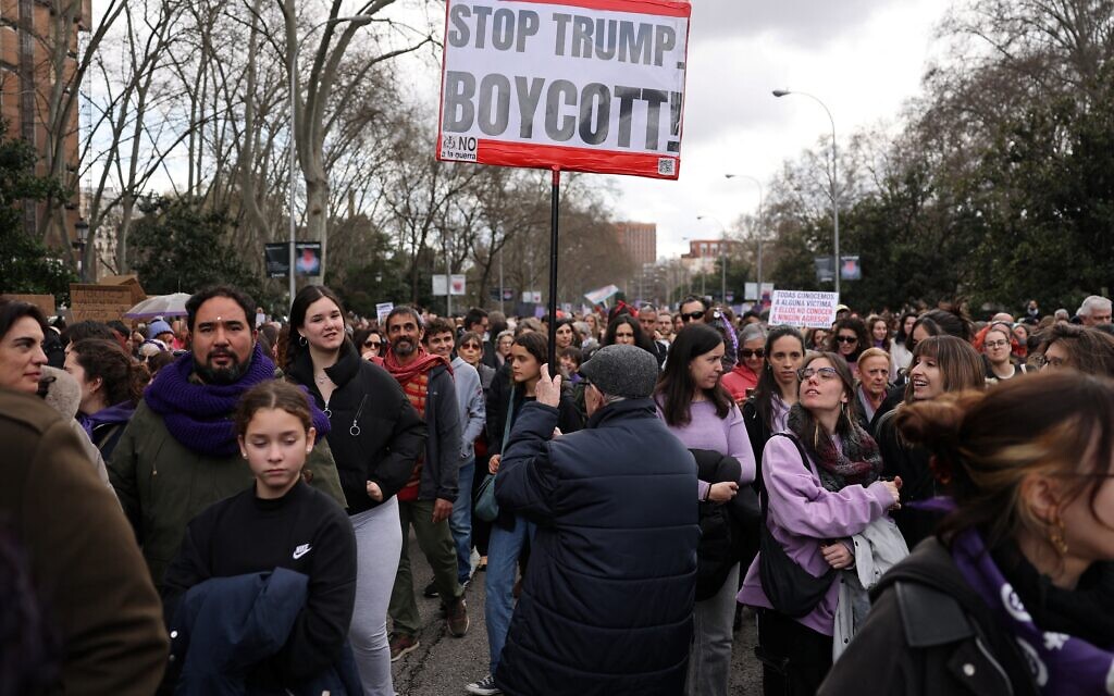 Un homme tenant une pancarte sur laquelle on peut lire « Stop Trump, boycott » et « Non à la guerre » lors d'une manifestation organisée à l'occasion de la Journée de la femme, à Madrid, le 8 mars 2026. (Crédit : Thomas Coex/AFP)