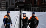 La police belge surveille le périmètre autour d’une synagogue de la rue Léon Frédéric après qu’elle a été frappée dans la nuit par une explosion à Liège, le 9 mars 2026. (Crédit : JOHN THYS/AFP)