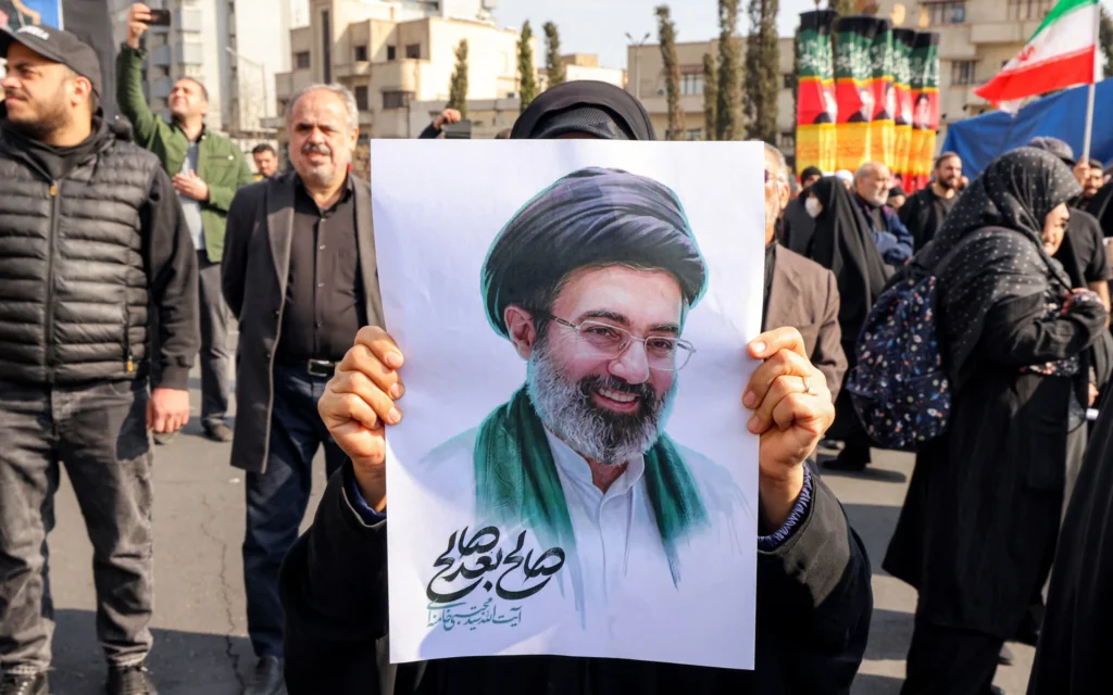 Une femme tenant une photo du nouveau guide suprême iranien, l'ayatollah Mojtaba Khamenei, lors d'un rassemblement en sa faveur sur la place Enghelab, dans le centre de Téhéran, le 9 mars 2026. (Crédit : Atta Kenare/AFP)