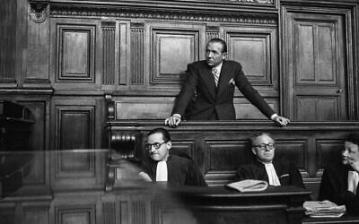 Le journaliste et homme politique français Jean Luchaire, qui était à la tête de la presse collaborationniste française à Paris pendant l'occupation militaire allemande, se tient dans le box des accusés derrière ses avocats lors de son procès à Paris, le 21 janvier 1946. (Crédit : AFP)