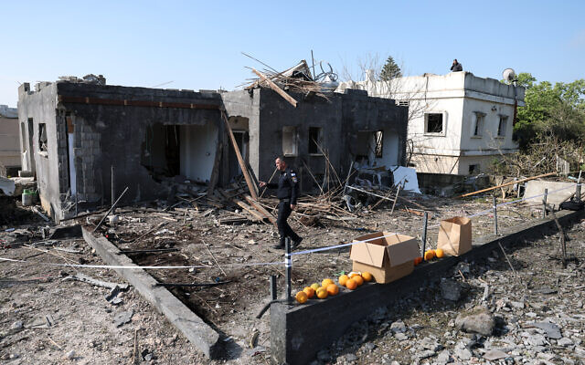 Un policier israélien inspecte le site d'un tir de roquette à Zarzir, dans le nord d'Israël, le 13 mars 2026. (Crédit : Odd ANDERSEN / AFP)