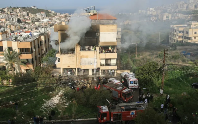 Des secouristes et des habitantssur le site d'une frappe aérienne israélienne qui a visé un immeuble, dans la ville de Haret Saïda, au sud du Liban, dans la banlieue de Saïda, le 14 mars 2026. (Crédit : Mahmoud Zayyat/ AFP)