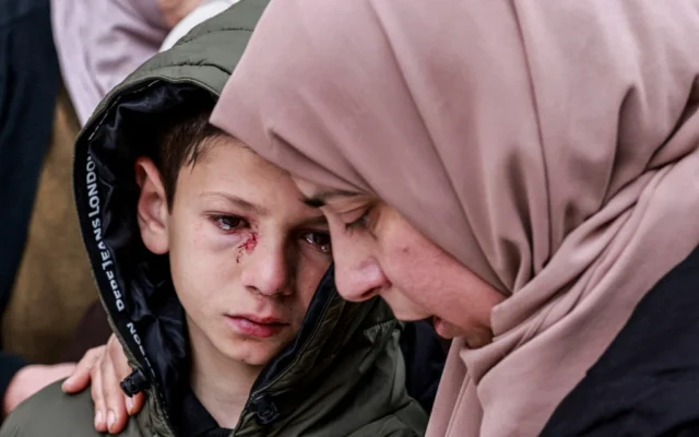 Mustafa, qui a été blessé mais a survécu aux tirs des soldats israéliens qui ont tué ses parents et ses deux frères et sœurs, est réconforté lors de leurs funérailles à Tammon, en Cisjordanie, le 15 mars 2026. (Jaafar ASHTIYEH / AFP)