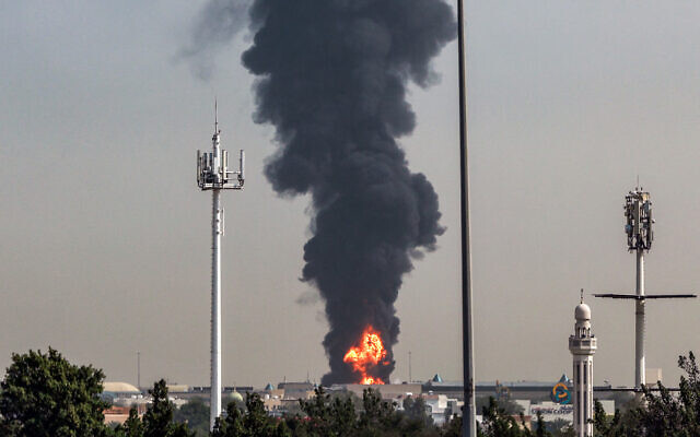Un panache de fumée s'élevant au-dessus d'un incendie en cours à l'aéroport international de Dubaï, le 16 mars 2026. Les vols reprenaient progressivement à l'aéroport de Dubaï le 16 mars, autrefois le plus fréquenté au monde pour les vols internationaux, a indiqué l'exploitant de l'aéroport, après qu'un « incident lié à un drone » a provoqué l'incendie d'un réservoir de carburant à proximité, alors que l'Iran poursuivait ses attaques dans le Golfe. (Crédit : AFP)