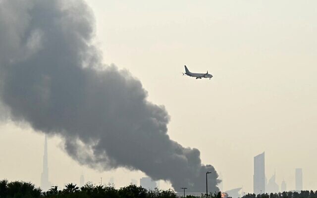 Un avion d'Emirates survolant les panaches de fumée d'un incendie en cours, près de l'aéroport international de Dubaï, le 16 mars 2026. (Crédit : AFP) Un avion d'Emirates survolant les panaches de fumée d'un incendie en cours, près de l'aéroport international de Dubaï, le 16 mars 2026. (Crédit : AFP)