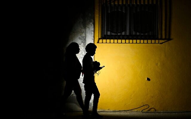 Une femme marche aux côtés d'un homme dans une rue de La Havane lors d'une coupure de courant, une lampe torche à la main, le 16 mars 2026. (Crédit : Yamil Lage/AFP) Une femme marche aux côtés d'un homme dans une rue de La Havane lors d'une coupure de courant, une lampe torche à la main, le 16 mars 2026. (Crédit : Yamil Lage/AFP)
