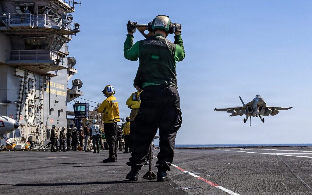 Cette photo fournie par l'US Navy, publiée le 18 mars 2026 par le service des relations publiques du Commandement central américain, montre des marins américains observant l'approche d'un avion F/A-18E Super Hornet, affecté à l'escadron de chasse 31 (Strike Fighter Squadron 31), sur le pont d'envol du plus grand porte-avions du monde, l'USS Gerald R. Ford (CVN 78), lors de l'opération Fureur épique, le 8 mars 2026 (Crédit : Service des relations publiques du NAVCENT / DVIDS / AFP)