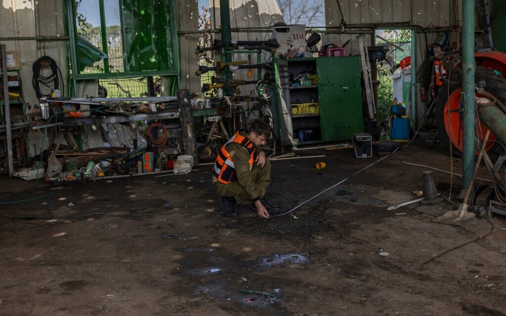 Un membre du Commandement du Front intérieur inspecte le lieu où un travailleur étranger a été tué lors d'une attaque de missiles iranienne qui a frappé le moshav Adanim, près de Hod Hasharon, dans le centre d'Israël, le 19 mars 2026 (Crédit : Ilia YEFIMOVICH / AFP)