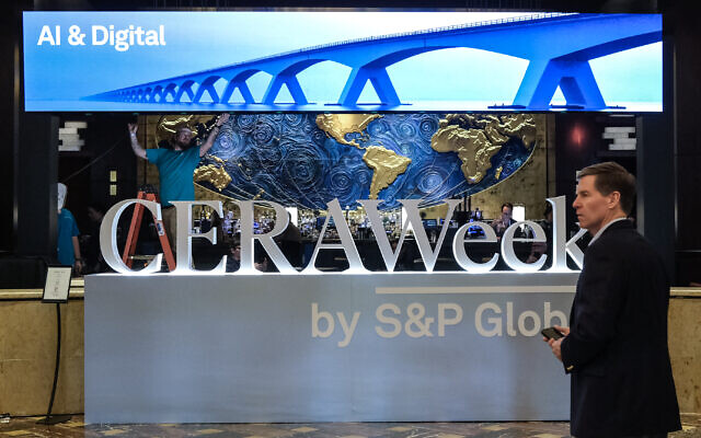 Un homme passant devant une affiche annonçant la CERAWeek, le salon annuel dédié au secteur de l'énergie organisé par S&P Global, à Houston, au Texas, le 22 mars 2026. (Crédit : Ronaldo Schemidt/AFP) Un homme passant devant une affiche annonçant la CERAWeek, le salon annuel dédié au secteur de l'énergie organisé par S&P Global, à Houston, au Texas, le 22 mars 2026. (Crédit : Ronaldo Schemidt/AFP)
