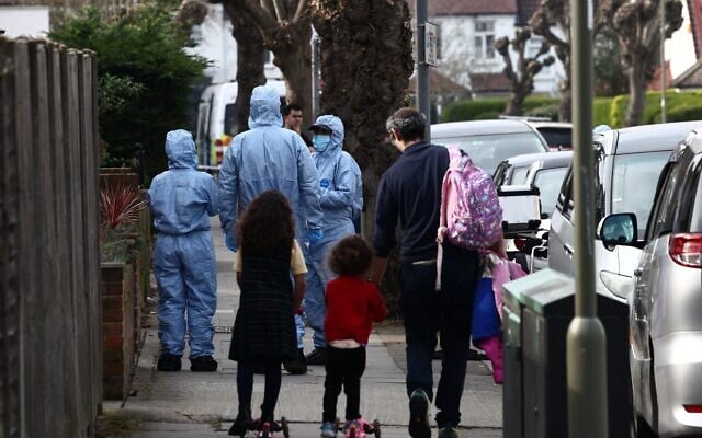 Une famille passe devant des techniciens de la police scientifique à l'œuvre dans une rue proche du lieu d'un incendie criminel antisémite survenu le 23 mars 2026 dans le quartier de Golders Green, au nord de Londres, au cours duquel des ambulances bénévoles gérées par une organisation juive ont été incendiées. (Crédit : Henry Nicholls / AFP) Une famille passe devant des techniciens de la police scientifique à l'œuvre dans une rue proche du lieu d'un incendie criminel antisémite survenu le 23 mars 2026 dans le quartier de Golders Green, au nord de Londres, au cours duquel des ambulances bénévoles gérées par une organisation juive ont été incendiées. (Crédit : Henry Nicholls / AFP)