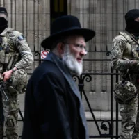 Des militaires belges armés de fusils d'assaut FN SCAR montent la garde devant une synagogue du centre d'Anvers, dans le cadre des mesures de sécurité renforcées mises en place par la Belgique dans les écoles juives et les synagogues, le 23 mars 2026. (Crédit: JOHN THYS / AFP)