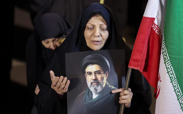 Une femme tient un portrait du guide suprême iranien Mojtaba Khamenei alors que des manifestants défilent en soutien aux forces armées iraniennes dans le centre de Téhéran, le 25 mars 2026. (Crédit : AFP)