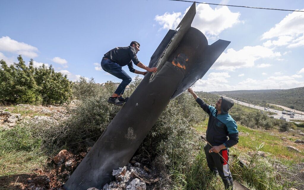 Un Palestinien grimpant sur les débris d’un missile iranien qui s’est abattu dans le village de Hares, en Cisjordanie, le 24 mars 2026. (Crédit : Jaafar Ashtiyeh/AFP)