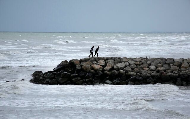 Deux hommes marchent sur une jetée de la côte sud de la mer Caspienne, dans la ville portuaire de Bandar Anzal, en Iran, le 2 décembre 2024. (Crédit : AP Photo/Vahid Salemi)