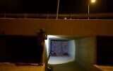 Un Bédouin éclairant avec sa lampe torche l'abri de fortune qu'il partage avec une centaine de membres de sa communauté pour les protéger des tirs iraniens, à proximité d'un canal de drainage près d'Arad, dans le sud d'Israël, le 17 juin 2025. (Crédit : Maya Alleruzzo/AP)