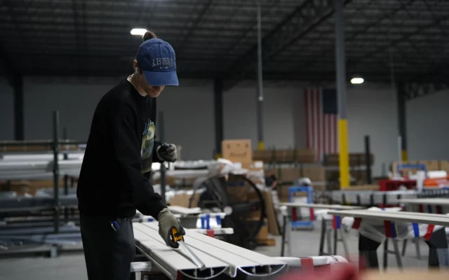 Un ouvrier prend les mesures d'une poutre en aluminium dans l'usine de The Luxury Pergola, une entreprise qui fabrique des pergolas en aluminium, le 20 février 2026, à Noblesville, dans l'Indiana. (Crédit : AP Photo/Obed Lamy)