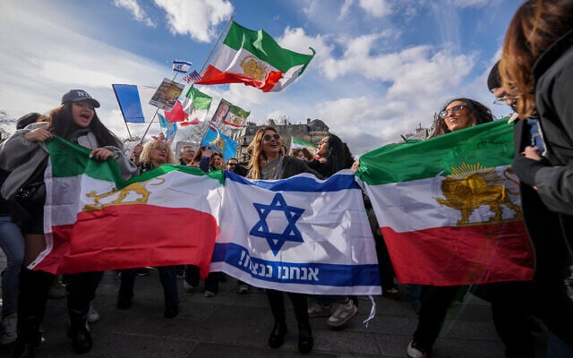Des membres de l'importante diaspora iranienne en France brandissant des drapeaux d'Israël et iraniens lors d'une manifestation organisée en réaction aux frappes américaines et israéliennes contre l'Iran, à Paris, le 1ᵉʳ mars 2026. (Crédit : Aurélien Morissard/AP)