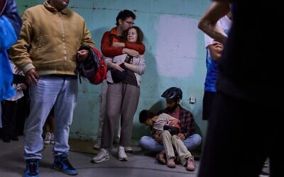 Les gens se mettant à l'abri alors que les sirènes annonçant l'arrivée de missiles iraniens retentissent, à Tel Aviv, le 7 mars 2026. (Crédit : Oded Balilty/AP Photo)