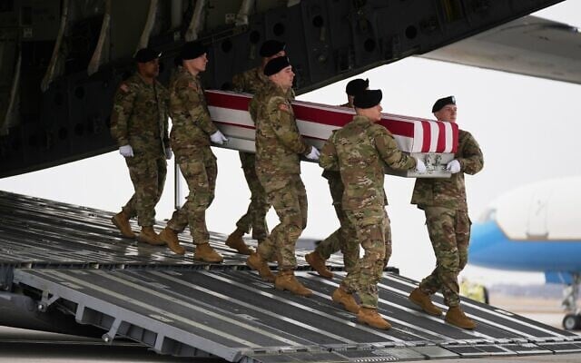 Une équipe de l'armée américaine transportant un cercueil recouvert du drapeau américain contenant la dépouille du sergent Declan Coady, 20 ans, originaire de West Des Moines, dans l'Iowa, tué lors d'une frappe de drone sur un centre de commandement au Koweït après le lancement de la campagne militaire américaine et israélienne contre la République islamique d'Iran, devant le président Donald Trump et la première dame Melania Trump lors d'une cérémonie de rapatriement des victimes, à la base aérienne de Dover, dans le Delaware, le 7 mars 2026. (Crédit : Mark Schiefelbein/AP)