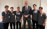Le ministre Tony Burke, au centre, pose dans un lieu tenu secret avec cinq footballeuses iraniennes qui ont obtenu l'asile en Australie le 10 mars 2026. (Crédit : Ministère australien de l'Intérieur via AP)