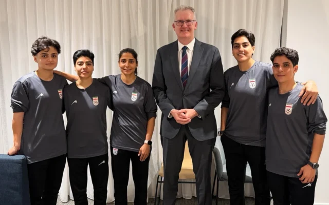 Le ministre Tony Burke, au centre, pose dans un lieu tenu secret avec cinq footballeuses iraniennes qui ont obtenu l'asile en Australie le 10 mars 2026. (Crédit : Ministère australien de l'Intérieur via AP)