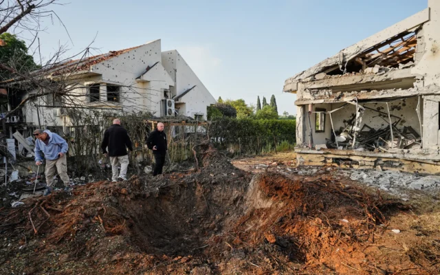 Des personnes inspectent des maisons endommagées par une roquette tirée par le Hezbollah depuis le Liban, à Haniel, dans le centre d'Israël, le 12 mars 2026. (Crédit : AP Photo/Baz Ratner)