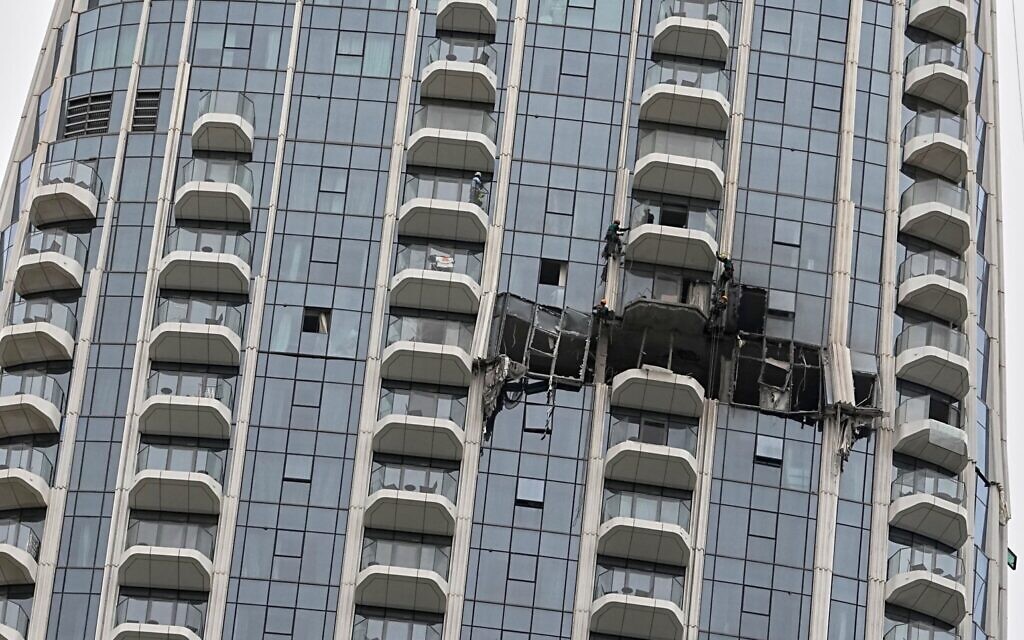 Des ouvriers inspectant les dégâts causés par une frappe de drone iranien pendant la nuit à l’hôtel Address Creek Harbour, à Dubaï, aux Émirats arabes unis, le 12 mars 2026. (Crédit : Fatima Shbair/AP)